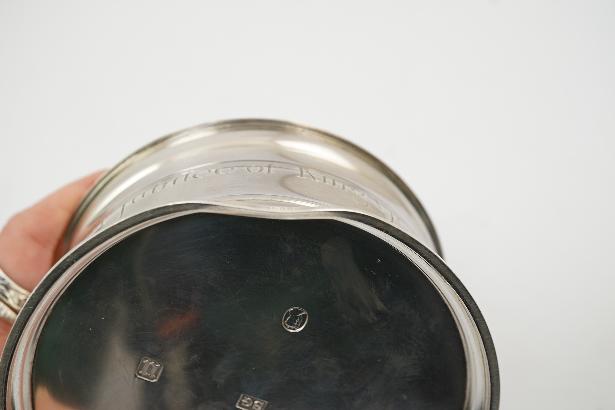 A George V silver circular inkwell, by Sebastian Garrard, commemorating the Silver Jubilee of King George V, the die stamped cover designed by George Kruger Gray featuring the Goldsmiths Company Coat of Arms